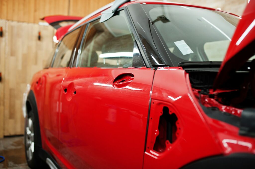 Car service red car body at the detailing vehicle workshop. Car protection with special films.